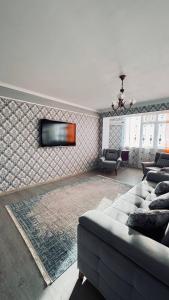 ein Wohnzimmer mit einem Sofa und einem TV an der Wand in der Unterkunft ЖК «Caspyi Towers», 17-й микрорайон, 3 дом , 2 подъезд, 15 этаж , 114 кв. in Aqtau
