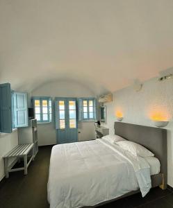 een slaapkamer met een groot wit bed en blauwe kasten bij Sunset Paradise Oia in Oia