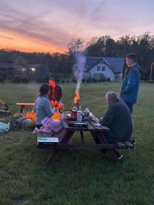 a group of people sitting around a picnic table with a fire at Agroturystyka u Krystyny in Moryń