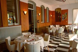 un comedor con mesas, sillas blancas y registrador en Logis Hotel des Lacs, en Celles-sur-Plaine