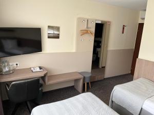 a hotel room with a desk and a tv on the wall at Hotel Zum Ritter in Seligenstadt
