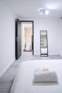 Una habitación blanca con una cama y un espejo. en La loge des Carmélites Coeur de Nantes WIFI, en Nantes