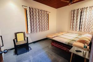 アリバグにあるSadhana Homestayのベッドと椅子のある寝室