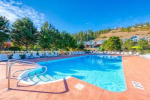 a swimming pool at a resort with chairs and trees at Belle Vue Cottage - Kelowna, BC in Kelowna