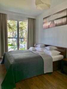 sypialnia z dużym łóżkiem i dużym oknem w obiekcie REMAR - Apartamenty nad Jeziorem Necko w mieście Augustów