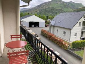 una casa y un balcón con una mesa y sillas rojas. en Gîte le Pic du Ger en Laruns