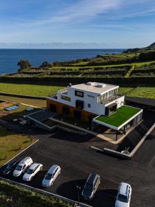 a building with cars parked in a parking lot next to the ocean at Xhale Azores in Angra do Heroísmo