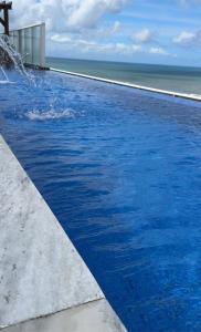 een blauw zwembad met de oceaan op de achtergrond bij Bugan Paiva/ Home stay in Recife