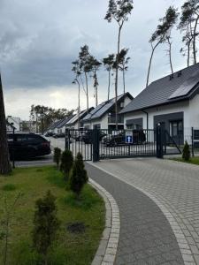 a cobblestone driveway with a black fence and houses at Apartament 7 - Maja in Dziwnówek