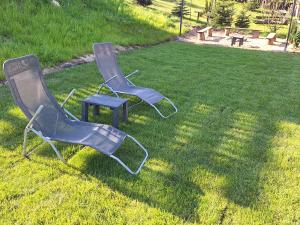 two chairs and a stool sitting in the grass at Domek Na Mazurach in Bogaczewo