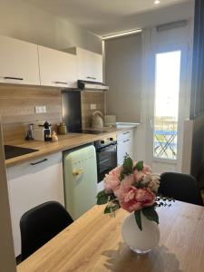 a kitchen with a table with a vase of flowers on it at Joli studio spacieux in Ajaccio