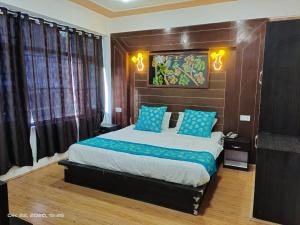 a bedroom with a large bed with blue pillows at HOTEL D INDIAN KARGIL in Kargil