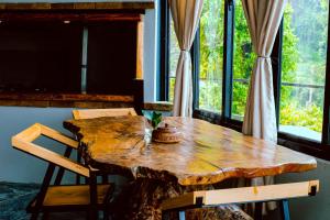 drewniany stół z 2 krzesłami i duże okno w obiekcie The Hideout Villa Pokhara w mieście Pokhara