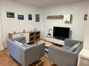sala de estar con 2 sillas y TV de pantalla plana en apartamento luanco playa, en Luanco