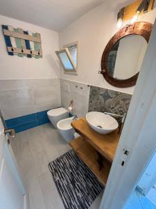 bagno con servizi igienici, lavandino e specchio di Mono 4 posti vista mare "Il Portolano" a Porto Azzurro