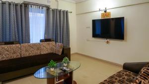 a living room with a couch and a tv on the wall at AP's Castle Stay in Kharadi +22 photos