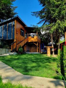 una gran casa de madera con un patio verde en Tiny House Căsuța cocoțată - Valea Doftanei - 2camere en Valea Doftanei