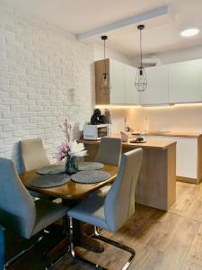 a kitchen and dining room with a wooden table and chairs at REMAR - Apartamentai prie Necko Ežero in Augustów