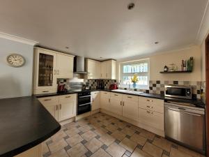 una cocina con armarios blancos y encimeras negras en Glens Reach Laugharne en Laugharne