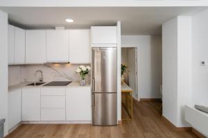 - un réfrigérateur en acier inoxydable dans une cuisine avec des placards blancs dans l'établissement Gravina Corner House, à Séville