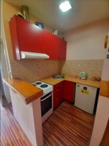 a small kitchen with red cabinets and a white stove at 2A Apartments Bascarsija in Sarajevo