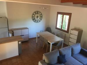 ein Wohnzimmer mit einer Couch, einem Tisch und einer Uhr in der Unterkunft Villa CASA CALLISTA , confort et calme in Sainte-Lucie de Porto-Vecchio