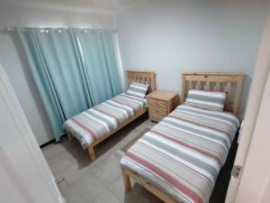2 Betten in einem Zimmer mit blauen Vorhängen in der Unterkunft Seashell Haven Hideout in Henties Bay