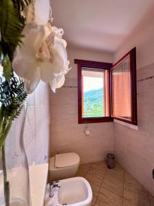 La salle de bains est pourvue de toilettes et d'un vase avec une fleur. dans l'établissement Angelina House Cisano, à Cisano Bergamasco