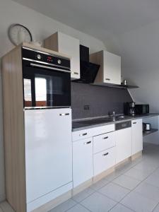 eine Küche mit weißen Schränken und einem Herd mit Backofen in der Unterkunft Ferienwohnung An der Karlskuppe in Eisenach + 11 Fotos
