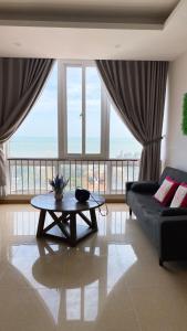 ein Wohnzimmer mit einem Tisch und einem großen Fenster in der Unterkunft Son Thinh Apartment in Vũng Tàu