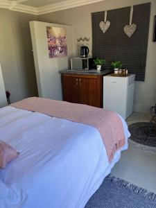 a bedroom with a white bed and a kitchen at Stellies Accommodation - Room 2 in Keetmanshoop