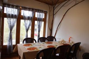 comedor con mesa, sillas y ventanas en Karma Lodge, en Leh