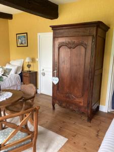 una sala de estar con un armario de madera y una mesa. en L'Armandière, en Sainte-Colombe