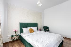 a bedroom with a large bed with a green headboard at ARI Yellow Apartment - Panoramic View in Arad