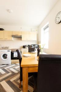 uma cozinha com uma mesa de madeira com cadeiras pretas em Cosy & Compact Apartment in Swinton em Manchester