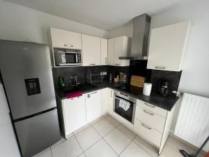 a kitchen with white cabinets and a black counter top at Joli T3 calme in Créteil