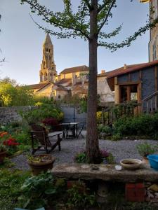 un jardín con un árbol y una iglesia al fondo en chambre d hôte "Sous le clocher", en Saint-Léonard-de-Noblat