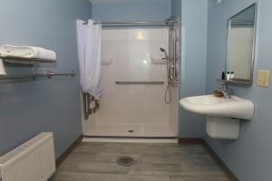 ein Bad mit einer Dusche und einem Waschbecken in der Unterkunft Wolastoq Inn And Suites in Houlton