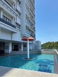 a pool with an umbrella in front of a building at Icon Residence Premium Condo in Kuala Terengganu