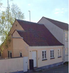 un petit bâtiment blanc avec un toit brun dans l'établissement Skønt byhus midt i Marstal., à Marstal