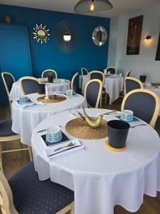 a dining room with white tables and chairs at Hôtel L'ideal le Mountbatten in Arromanches-les-Bains