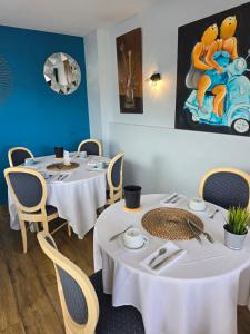 two tables in a restaurant with white tables and chairs at Hôtel L'ideal le Mountbatten in Arromanches-les-Bains