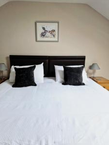 a bedroom with a large white bed with black pillows at Gwilym's Stable in Builth Wells