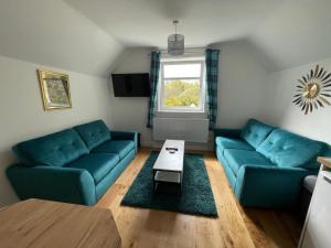 a living room with two blue couches and a table at Crannach House in Ballater