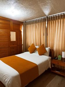 1 dormitorio con 1 cama con sábanas blancas y almohadas de color naranja en Hotel Tuvalu, en Paipa