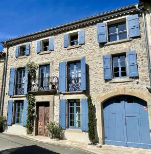 un edificio de piedra con puertas y ventanas azules en L'oiseau Bleu suite MERLE BLEU, en Roubia