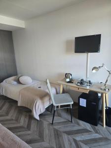 a hotel room with a bed and a desk with a chair at Hôtel L'ideal le Mountbatten in Arromanches-les-Bains