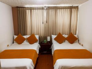 2 camas en una habitación de hotel con almohadas naranjas en Hotel Tuvalu, en Paipa