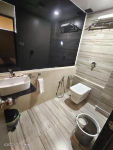 a bathroom with a sink and a toilet and a mirror at New Axis International By Glitz Hotels in Mumbai