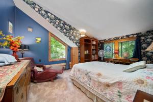 a bedroom with blue walls and a bed and a chair at Beautiful Log Cabin Wooded Lake Access Interlochen Arts Academy in Interlochen